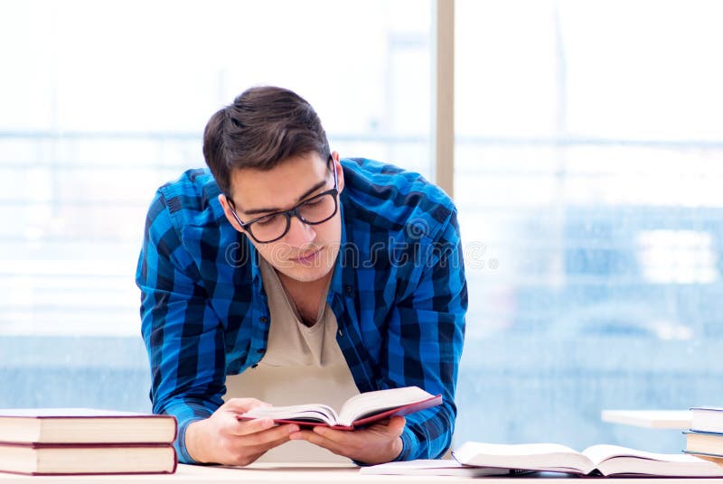Estudiante estudiando en la biblioteca vacía con un libro preparándose para ex. fotografía de archivo libre de regalías