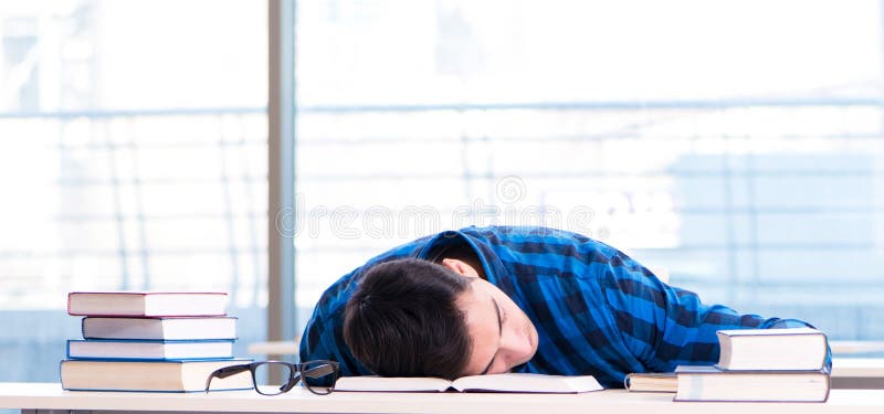 Estudiante estudiando en la biblioteca vacía con un libro preparándose para ex fotos de archivo