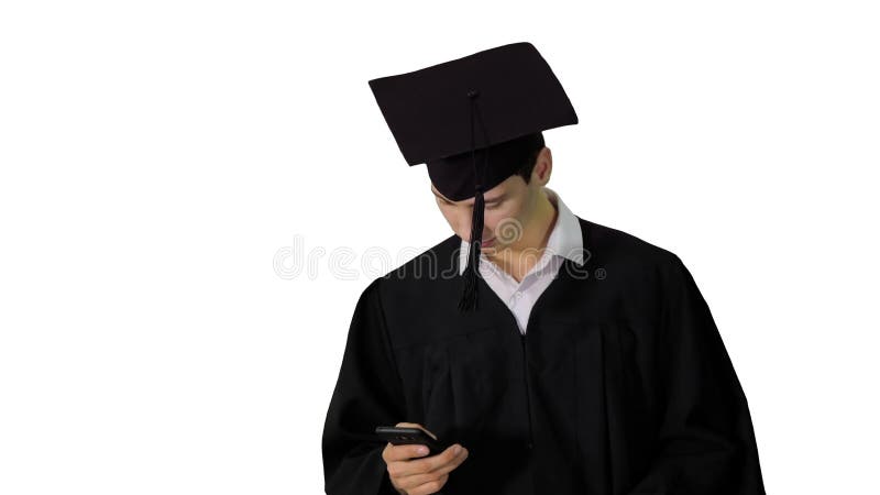 Estudiante graduado caminando mano mensajes de texto en el teléfono sobre fondo blanco. almacen de metraje de vídeo