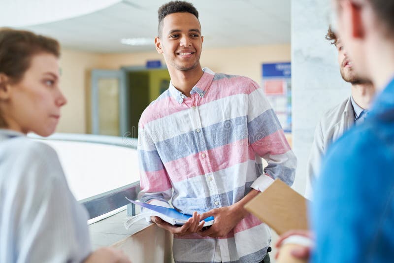 Estudiante hermoso sonriente que habla con los groupmates imágenes de archivo libres de regalías Estudiante hermoso sonriente que habla con los groupmates imágenes de archivo libres de regalías
