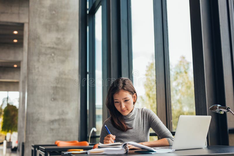 Estudiante joven que estudia en biblioteca fotografía de archivo libre de regalías
