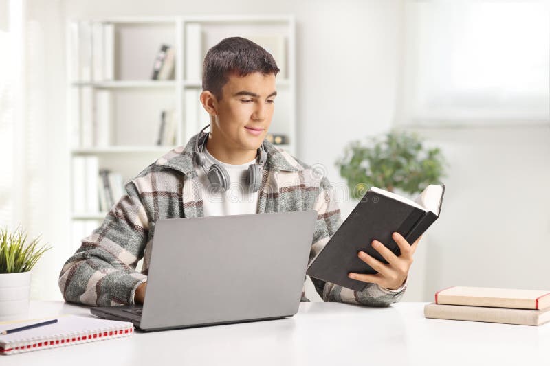Estudiante masculino estudiando con una computadora portátil y un libro fotografía de archivo libre de regalías