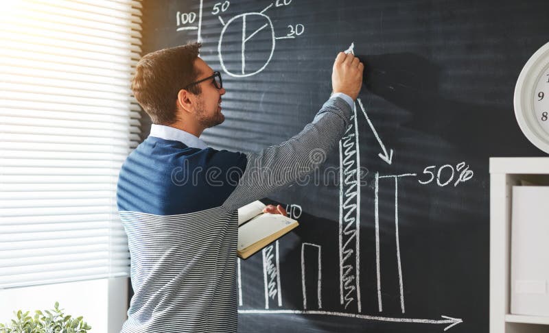 Estudiante masculino feliz, profesor, freelancer con tiza en la pizarra imagen de archivo libre de regalías Estudiante masculino feliz, profesor, freelancer con tiza en la pizarra imagen de archivo libre de regalías