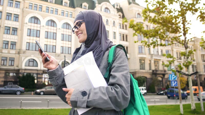 Estudiante musulmán confiado inspirado que charla en el teléfono, colocándose en la calle fotos de archivo libres de regalías Estudiante musulmán confiado inspirado que charla en el teléfono, colocándose en la calle fotos de archivo libres de regalías
