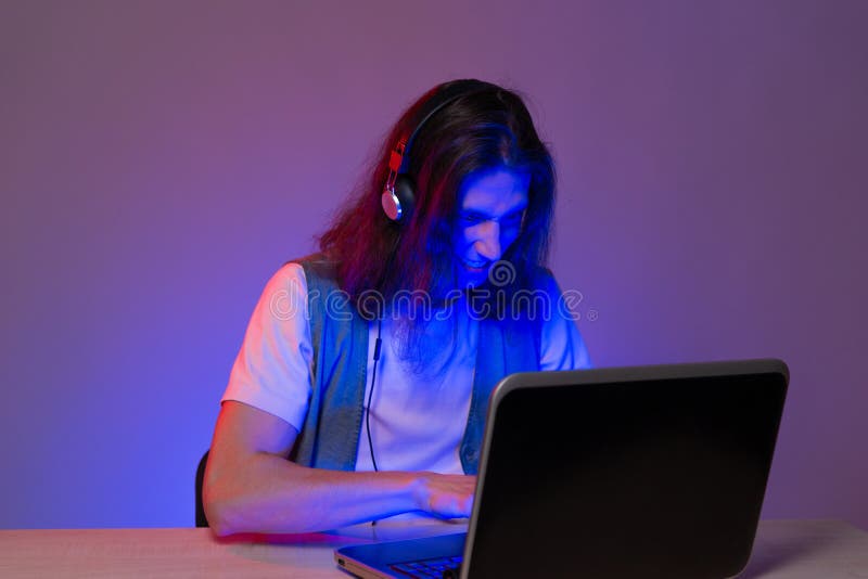 Estudiante o programador en un portátil retrato en teñido de neón. chico gracioso geek escribe código. imagen de archivo