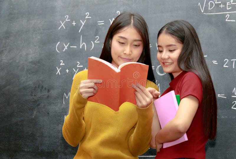 Estudiante universitario asiático feliz dos sobre los libros de lectura de la pizarra fotografía de archivo libre de regalías Estudiante universitario asiático feliz dos sobre los libros de lectura de la pizarra fotografía de archivo libre de regalías