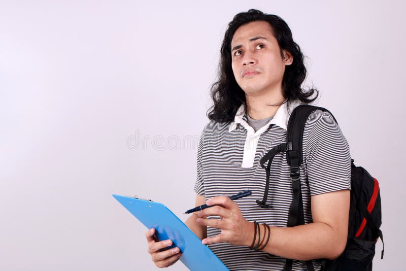 Estudiante universitario asiático sostiene portapapeles y piensa fotografía de archivo libre de regalías