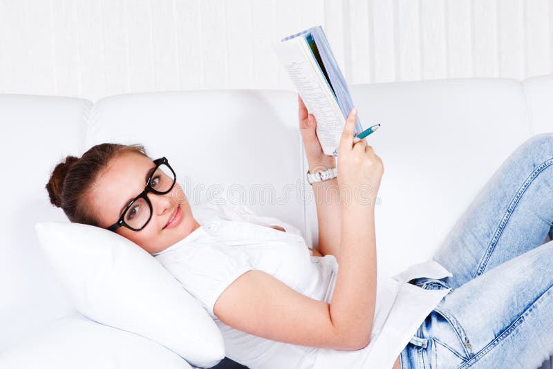 College student lying on sofa and reading a book. College student lying on sofa and reading a book