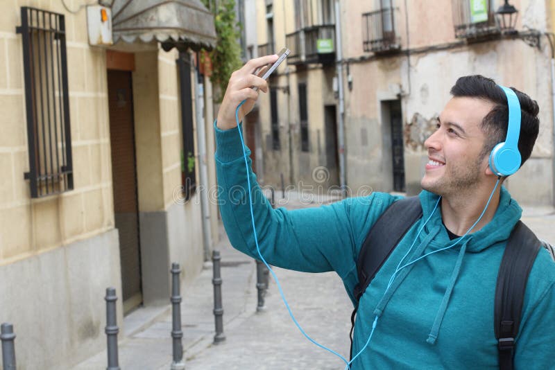 Estudiante étnico de moda que dirige a la universidad que toma un selfie con su smartphone imagen de archivo Estudiante étnico de moda que dirige a la universidad que toma un selfie con su smartphone imagen de archivo