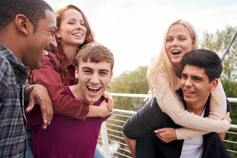 Estudiantes amigos y hombres que dan a las mujeres paseos por el Puente de la Ciudad imágenes de archivo libres de regalías