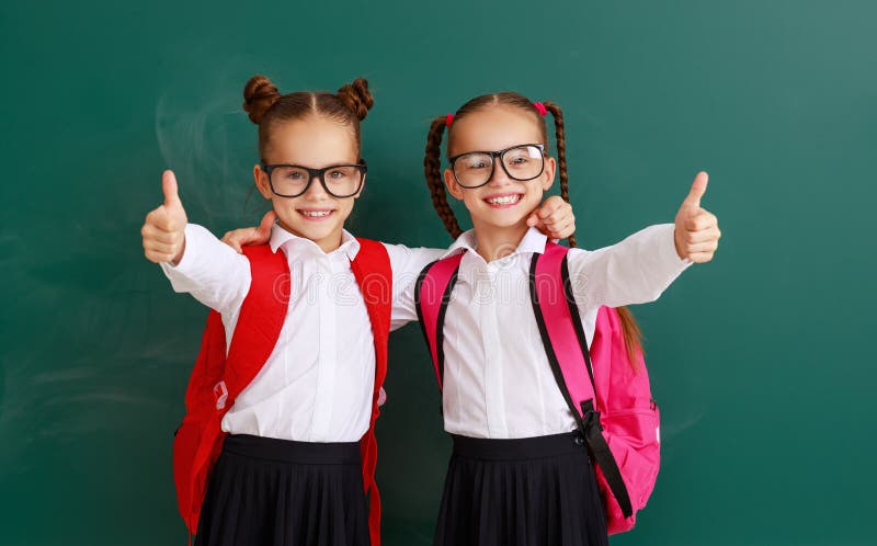 Estudiantes divertidos de los gemelos de las muchachas de las colegialas de los niños sobre la pizarra de la escuela imágenes de archivo libres de regalías Estudiantes divertidos de los gemelos de las muchachas de las colegialas de los niños sobre la pizarra de la escuela imágenes de archivo libres de regalías
