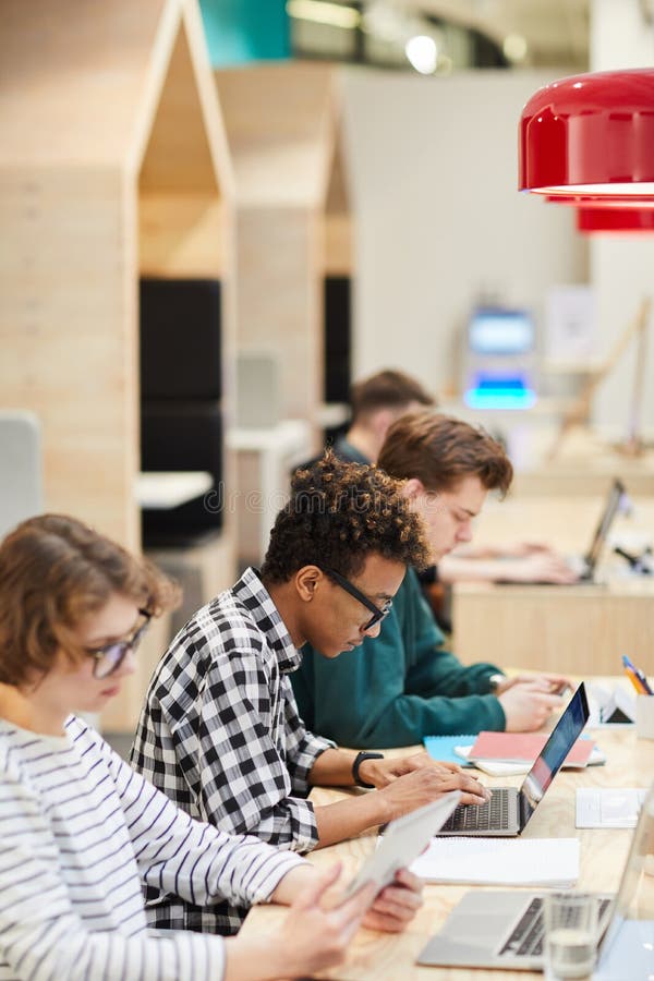 Estudiantes en la línea que hace el hometask en biblioteca imagenes de archivo Estudiantes en la línea que hace el hometask en biblioteca imagenes de archivo