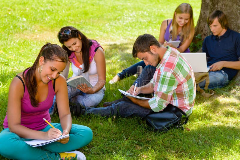 Estudiantes que se sientan en el parque que estudia la escritura de la lectura foto de archivo libre de regalías