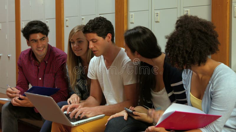 Estudiantes sonrientes que usan el ordenador portátil en vestuario