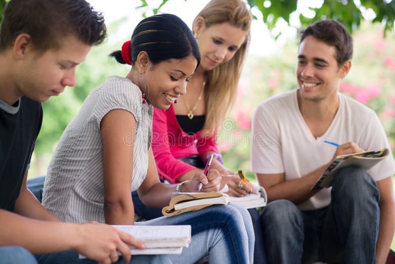 Estudiantes universitarios que hacen homeworks en parque imagen de archivo libre de regalías