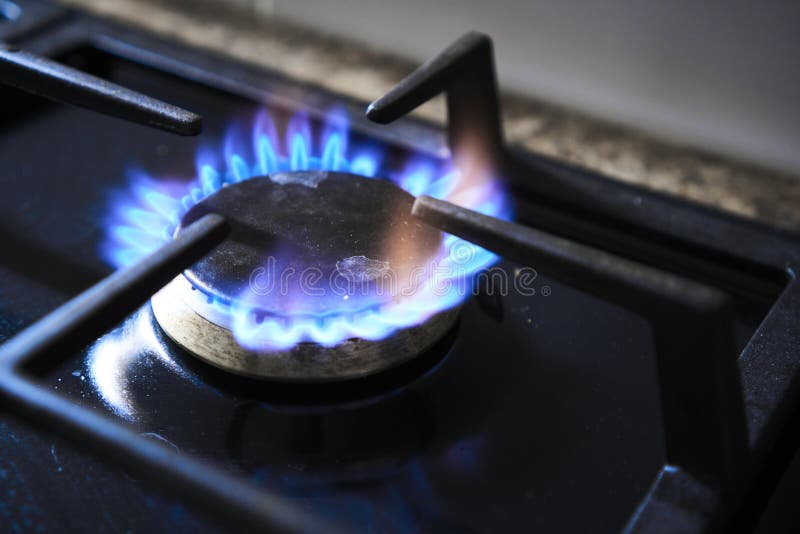 Una imagen bien enfocada que captura las intensas llamas azules de un  quemador de estufa de gas propano en una cocina hogareña