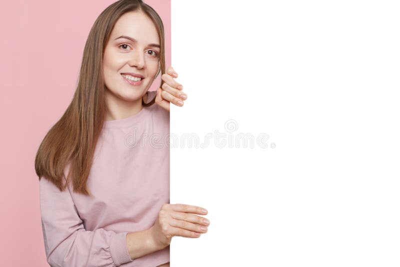 Estúdio disparado da mulher parecendo jovem agradável alegre na roupa ocasional, do lugar das posses espaço vazio, branco para su foto de stock royalty free Estúdio disparado da mulher parecendo jovem agradável alegre na roupa ocasional, do lugar das posses espaço vazio, branco para su foto de stock royalty free