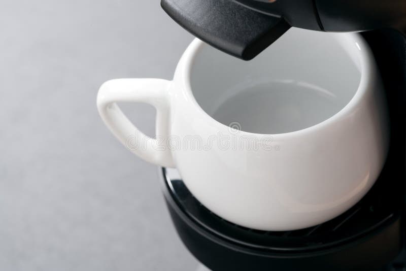 Esvazie o copo de café branco na máquina do café, close-up