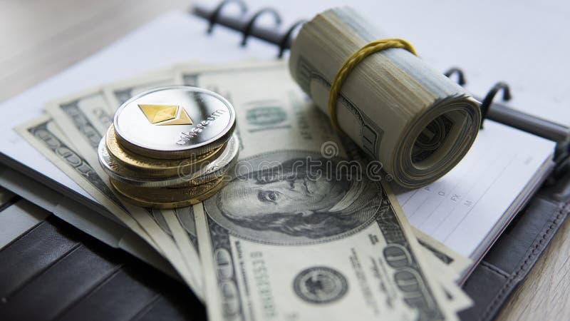 Ethereum crypto currency on top of 100 dollar biils on notepad. Profit from mining crypto currencies. Miner with dollars stock photo Ethereum crypto currency on top of 100 dollar biils on notepad. Profit from mining crypto currencies. Miner with dollars stock photo