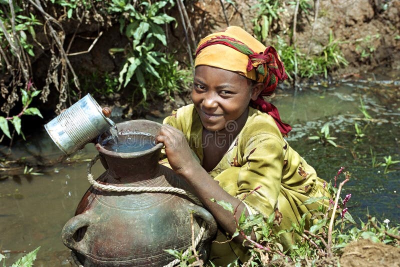 Ethiopia: portrait of Oromo girl, largest ethnic population group in Ethiopia, from the village Chancho Gabo Robi, gets drinking water from a stream, water source, for domestic consumption. The water in the area, given the drought, is scarce. To carry the filled traditional pitcher is heavy work for the girl. Child labor, labour, in Ethiopia is widespread. In many places in Ethiopia, Africa, people do not have sufficiently clean drinking-water, but this people, who live in very poor living conditions, have at least drinking water for a part of the year. She fills the stone jug with an empty tin can, recycling or reuse. Ethiopia: portrait of Oromo girl, largest ethnic population group in Ethiopia, from the village Chancho Gabo Robi, gets drinking water from a stream, water source, for domestic consumption. The water in the area, given the drought, is scarce. To carry the filled traditional pitcher is heavy work for the girl. Child labor, labour, in Ethiopia is widespread. In many places in Ethiopia, Africa, people do not have sufficiently clean drinking-water, but this people, who live in very poor living conditions, have at least drinking water for a part of the year. She fills the stone jug with an empty tin can, recycling or reuse.