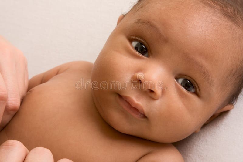 Riflessivo biracial mix di Ispanici e afroamericani bambino sdraiato su di colore giallastro coperta.