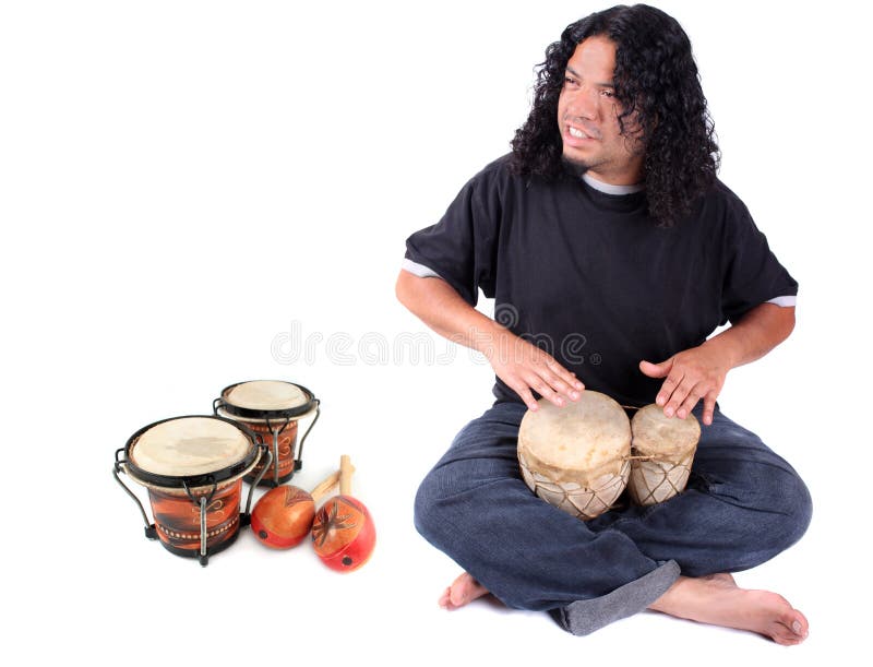 Funky long haired ethnic African American and Native Indian male playing bongo drums on a white background with other latin instruments to the side like maracas and another set of drums. Funky long haired ethnic African American and Native Indian male playing bongo drums on a white background with other latin instruments to the side like maracas and another set of drums