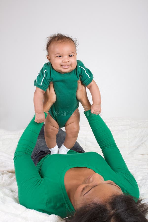 Ethnic mother playing with her baby boy son on bed royalty free stock image