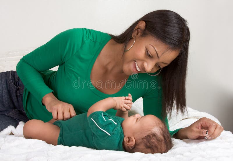 Ethnic mother playing with her baby boy son on bed stock photos