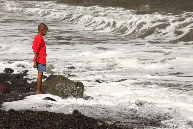 Ethnic school boy on beach watching the surf