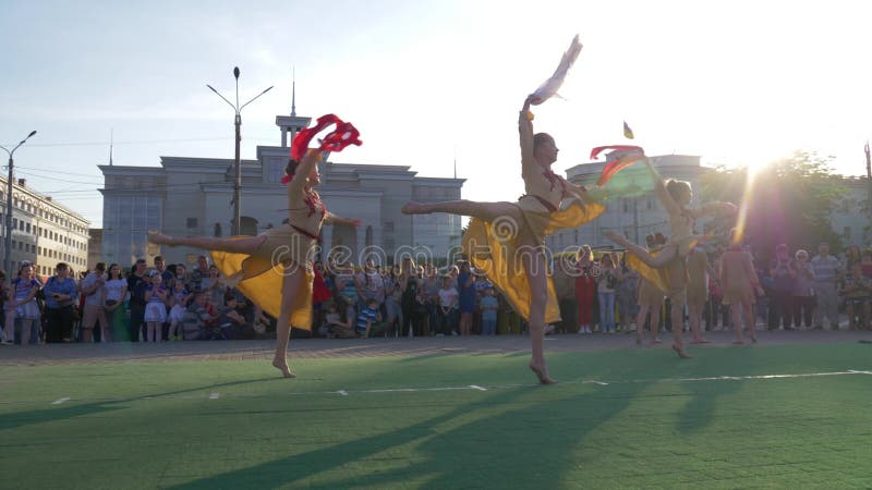 Ethnische Unterhaltung, Gruppe der jungen Frau in den Trachtenkleidern, die an in Stadtbereich vor Mengenöffentlichkeit tanzen