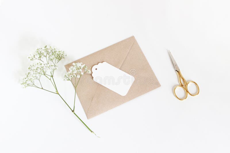 Etiqueta branca do presente com o envelope do papel do ofício, as tesouras douradas e as flores do Gypsophila da respiração do ` imagem de stock royalty free Etiqueta branca do presente com o envelope do papel do ofício, as tesouras douradas e as flores do Gypsophila da respiração do ` imagem de stock royalty free