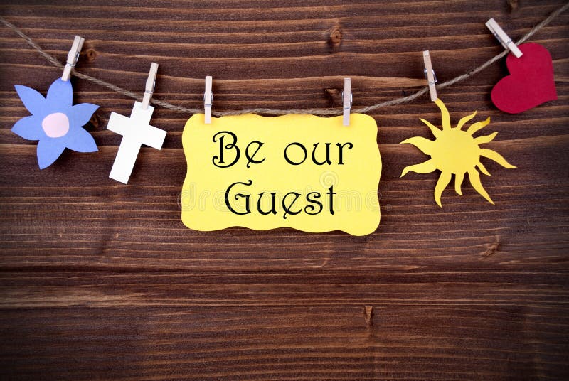 Hanging Tag with the Words Be Our Guest and Some Symbolics on Wood. Hanging Tag with the Words Be Our Guest and Some Symbolics on Wood