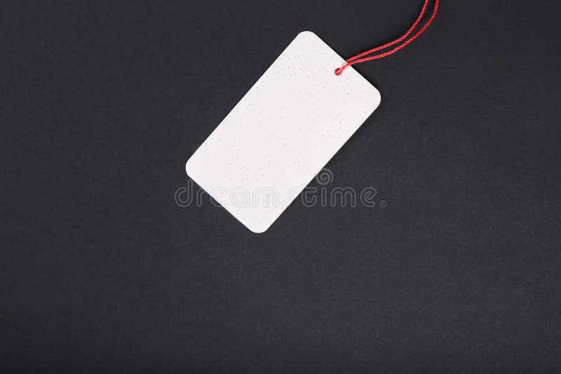 Etiqueta decorativa de la cartulina del espacio en blanco con el lazo rojo de la guita en fondo negro imagenes de archivo Etiqueta decorativa de la cartulina del espacio en blanco con el lazo rojo de la guita en fondo negro imagenes de archivo