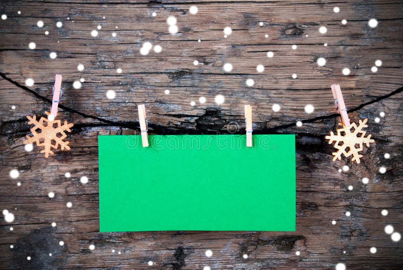 Empty Green Label with Copy Space on a Line with Snowflakes Hanging in the Snow in front of Rustic Wood. Empty Green Label with Copy Space on a Line with Snowflakes Hanging in the Snow in front of Rustic Wood