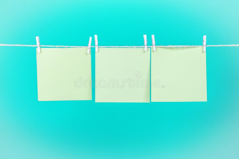 Etiquetas engomadas verdes en cuerda para tender la ropa con las pinzas aisladas en fondo azul imagenes de archivo Etiquetas engomadas verdes en cuerda para tender la ropa con las pinzas aisladas en fondo azul imagenes de archivo