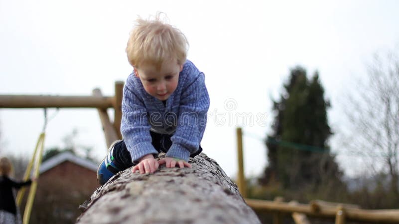 Ett barn klättrar på en logg i en park