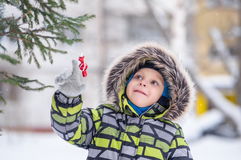 Ett barn undersöker ett trädgårdschristmas-träd på gatan på en snövinter fotografering för bildbyråer
