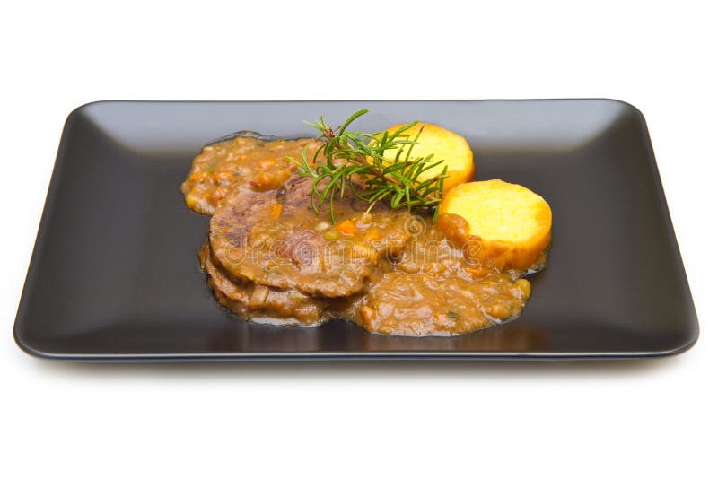 Ett bräserat kött med polenta på vit arkivbild