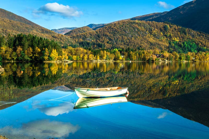 Ett ensamt fartyg och berg reflekterade i Haukeland sjön i drömlik, färgrik och stillsam höst i Bergen, Hordaland, Norge royaltyfri fotografi Ett ensamt fartyg och berg reflekterade i Haukeland sjön i drömlik, färgrik och stillsam höst i Bergen, Hordaland, Norge royaltyfri fotografi