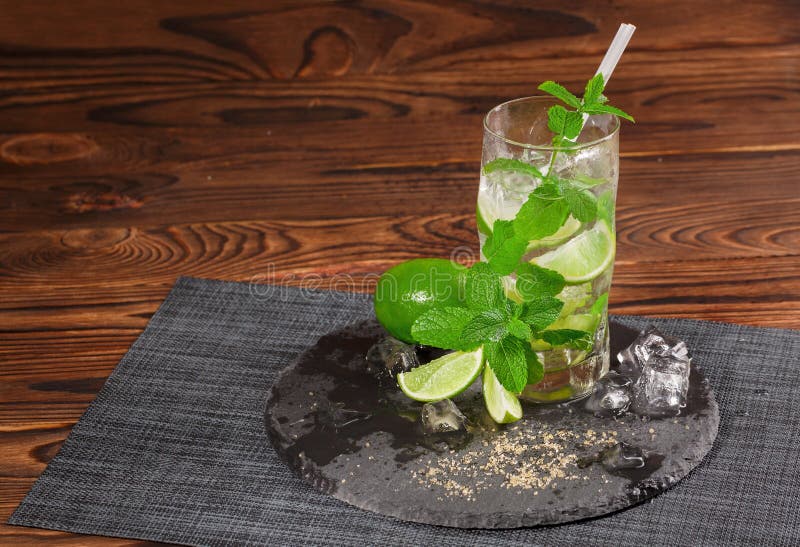 Ett exponeringsglas av grön mojito Sur, kall och alkoholiserad mojito med limefrukt och mintkaramellen Alkoholdrink på en träbakg arkivbild Ett exponeringsglas av grön mojito Sur, kall och alkoholiserad mojito med limefrukt och mintkaramellen Alkoholdrink på en träbakg arkivbild