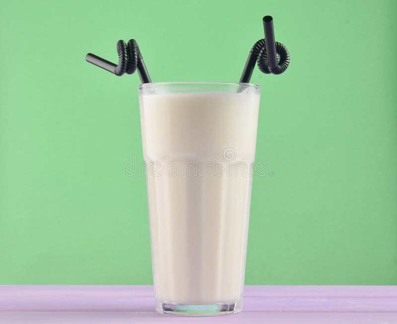 Ett exponeringsglas av milkshake med ett svart sugrör på en träpastellfärgad färg royaltyfria bilder Ett exponeringsglas av milkshake med ett svart sugrör på en träpastellfärgad färg royaltyfria bilder