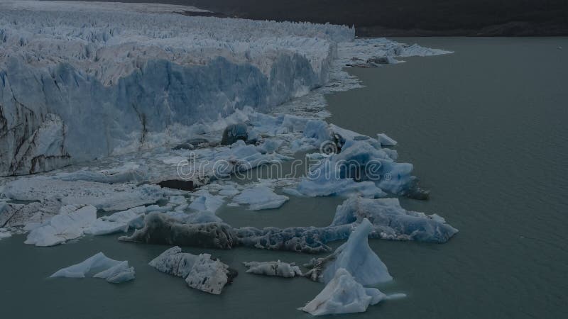 Ett fragment av smältande glaciär. en vägg med blå is över en glaciärsjö med turkos. arkivfoton