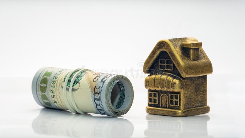 Ett guld- hus för leksak står bredvid en rulle av USA hundra dollarräkningar Begreppet intecknar, lånar ut, förpliktar, den finan arkivfoton Ett guld- hus för leksak står bredvid en rulle av USA hundra dollarräkningar Begreppet intecknar, lånar ut, förpliktar, den finan arkivfoton