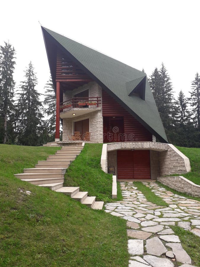 Ett härligt hus för berg på en kulle lokaliseras i skogen bredvid sjön royaltyfri bild Ett härligt hus för berg på en kulle lokaliseras i skogen bredvid sjön royaltyfri bild