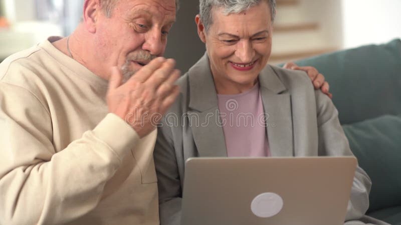 Ett lyckligt pensionerat par har ett videosamtal medan de sitter på soffan. Maka som pratar om videosamtal