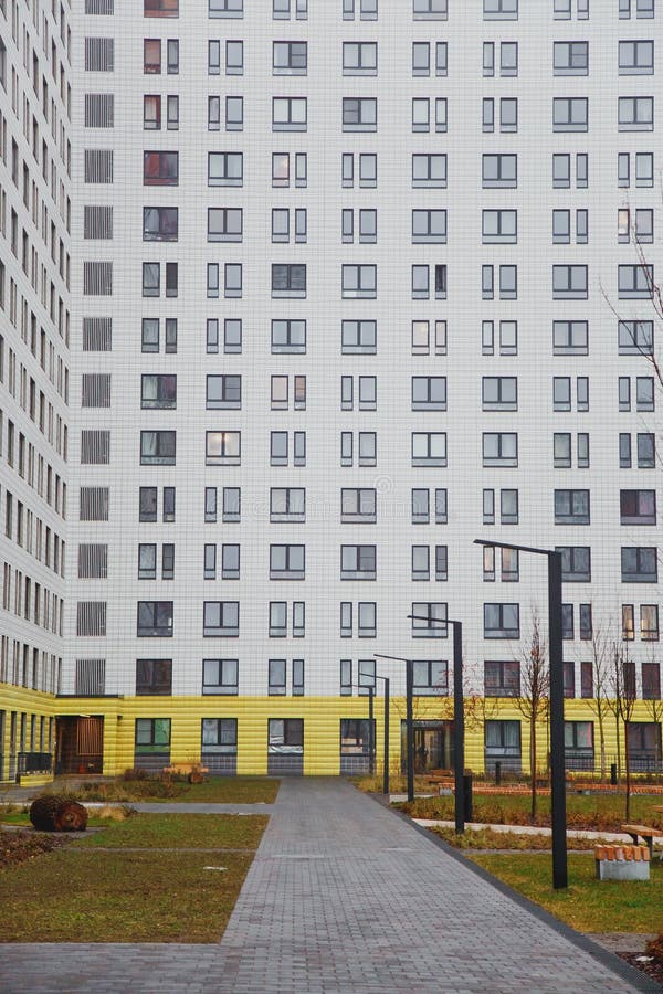 Ett minimalistiskt modernt gård i en lägenhetshus i staden, huset är gulvitt, vägar royaltyfri bild