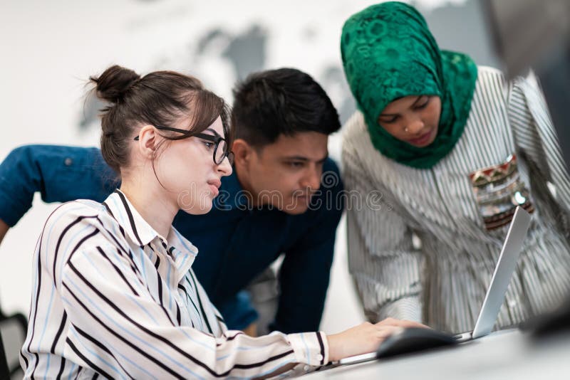 Ett multietniskt startteam, arabisk kvinna med hijab på möte i det moderna, öppna planeringskontoret i inlandet royaltyfri foto