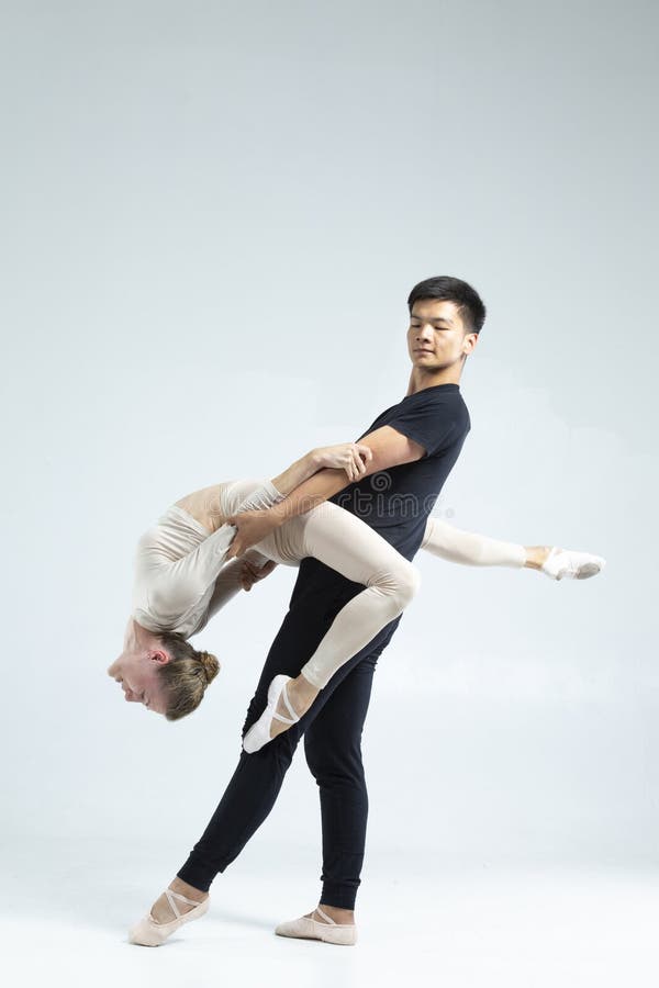 Ett par asiatiska män och kaukasiska kvinnor som utför säcksdansare på grå i Studio under föreställningar som klassiskt dansande o arkivfoto