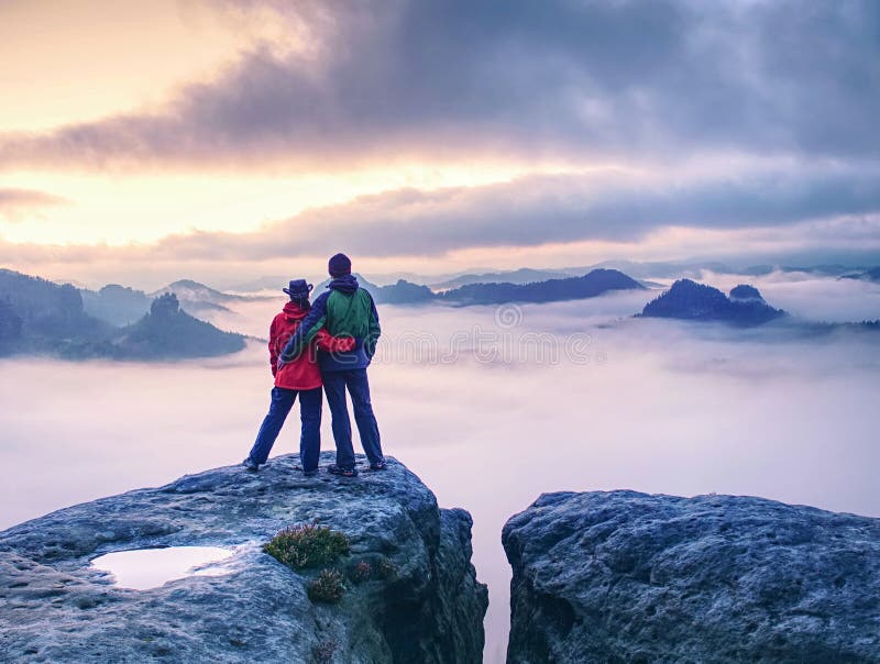Ett par på berget som ser över den tunga dimman till horisonten