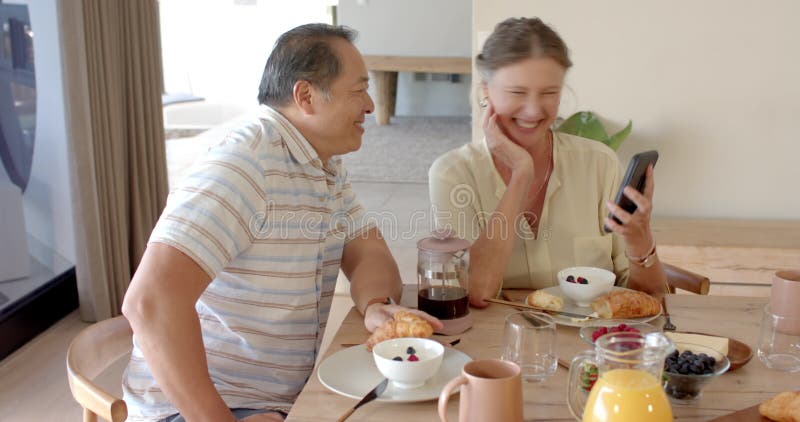 Ett par som gillar frukost och ser smartphone tillsammans arkivfilmer